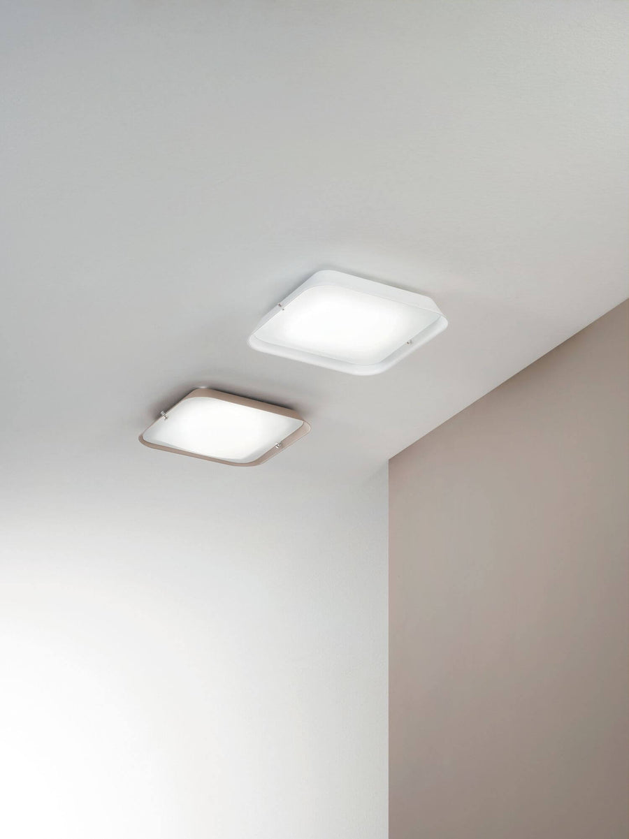 Vue en contre-plongée de deux plafonniers blancs sur plafond clair