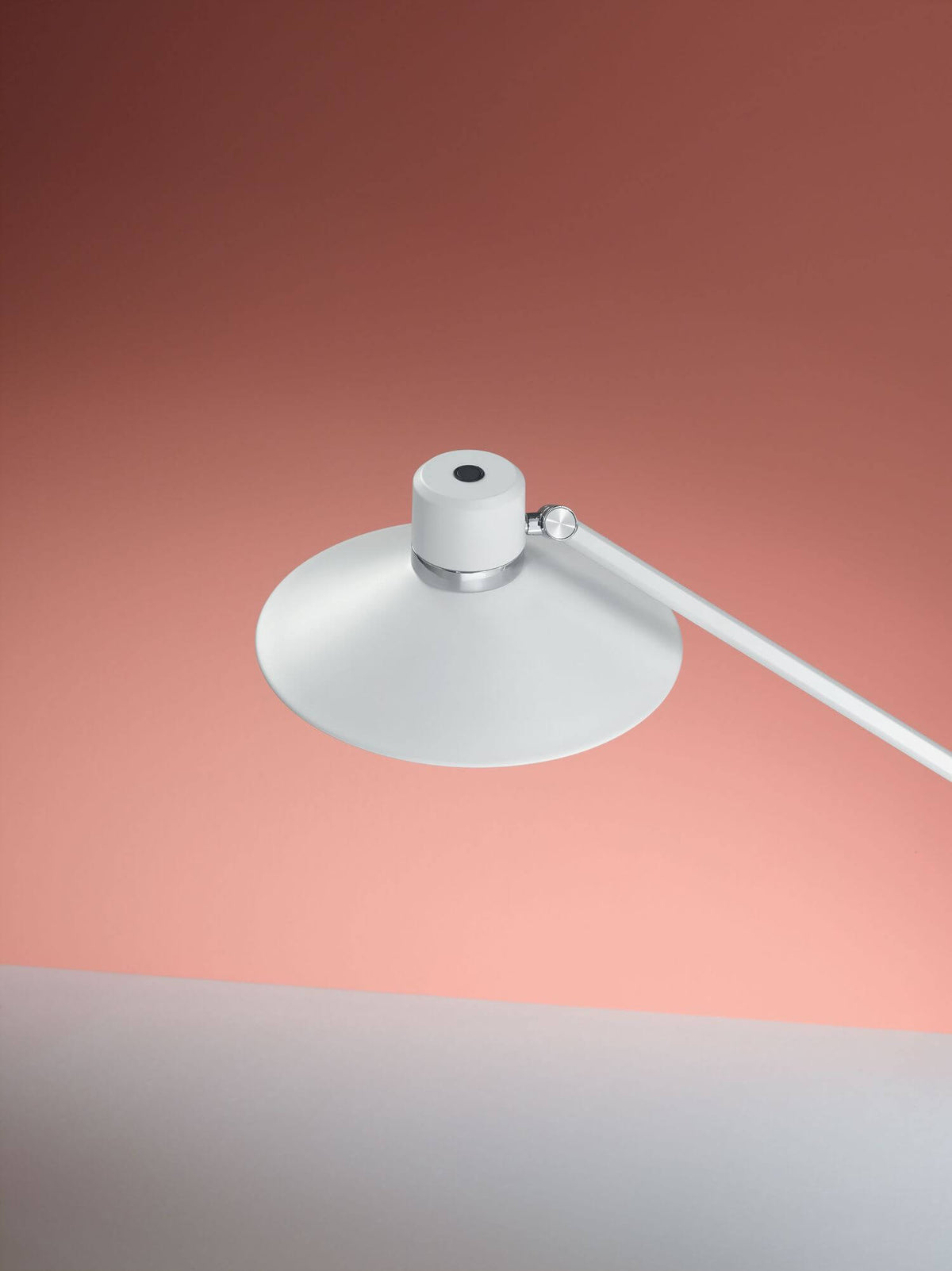 Détail de l'abat-jour conique blanc et de l'articulation chromée, fond rose