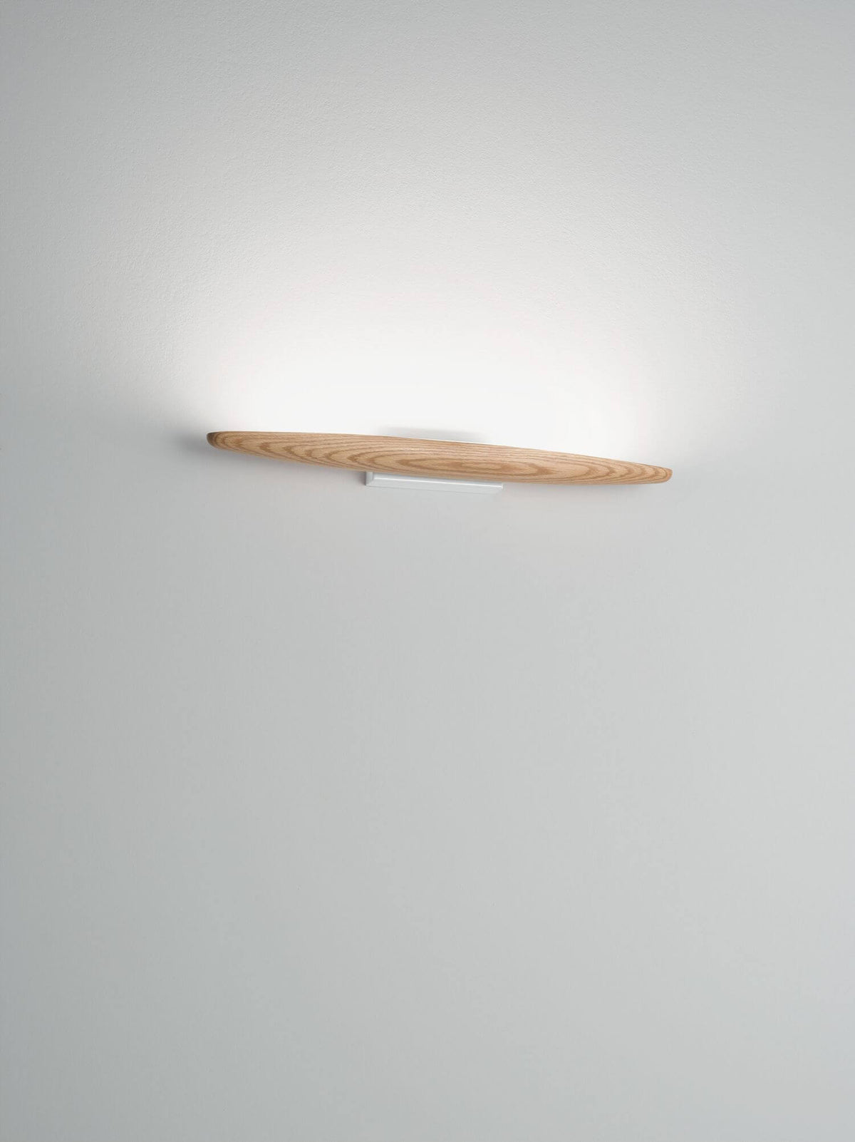 Mise en ambiance de l'applique allumée sur mur blanc, lumière diffuse vers le haut