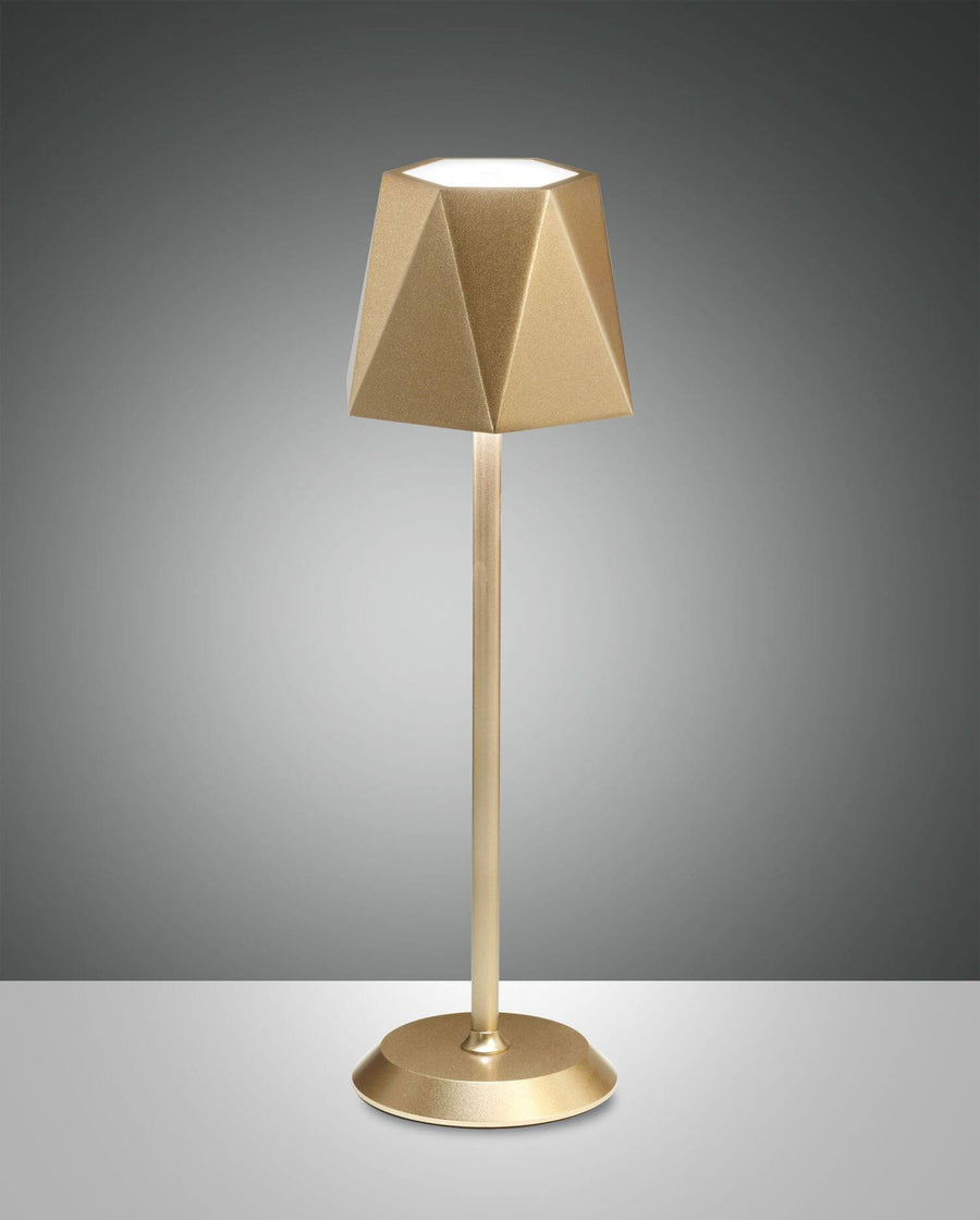 Lampe dorée de face, abat-jour géométrique facetté et socle rond métallique