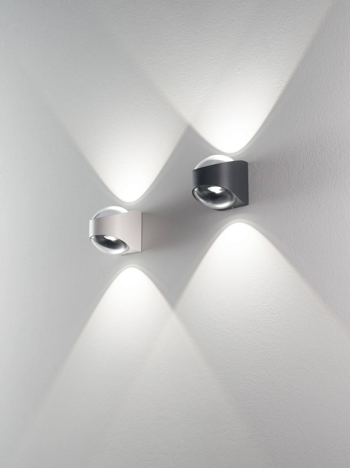 Mise en ambiance : deux appliques, noire et blanche, projetant des cônes de lumière sur un mur