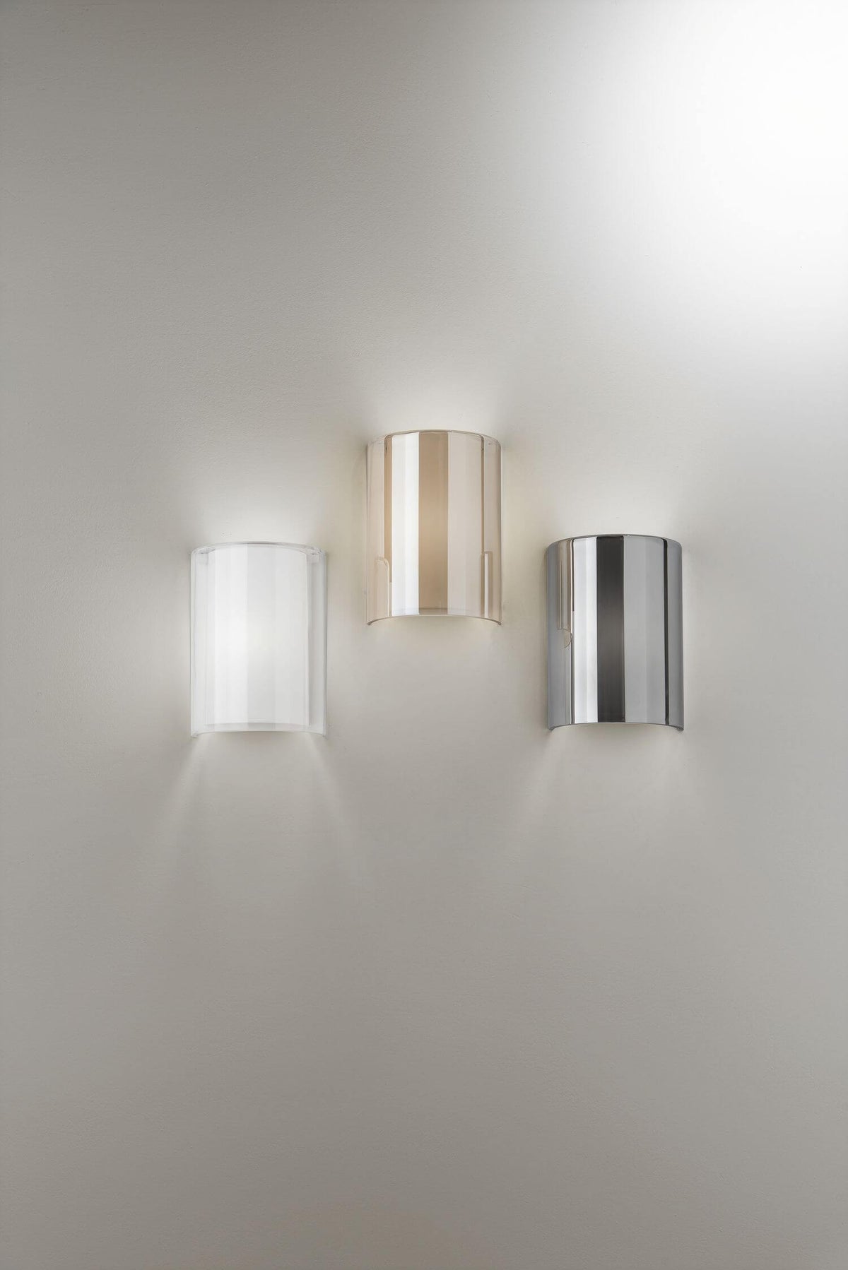 Trois appliques murales cintrées de face, coloris transparent, ambre rosé et chrome poli