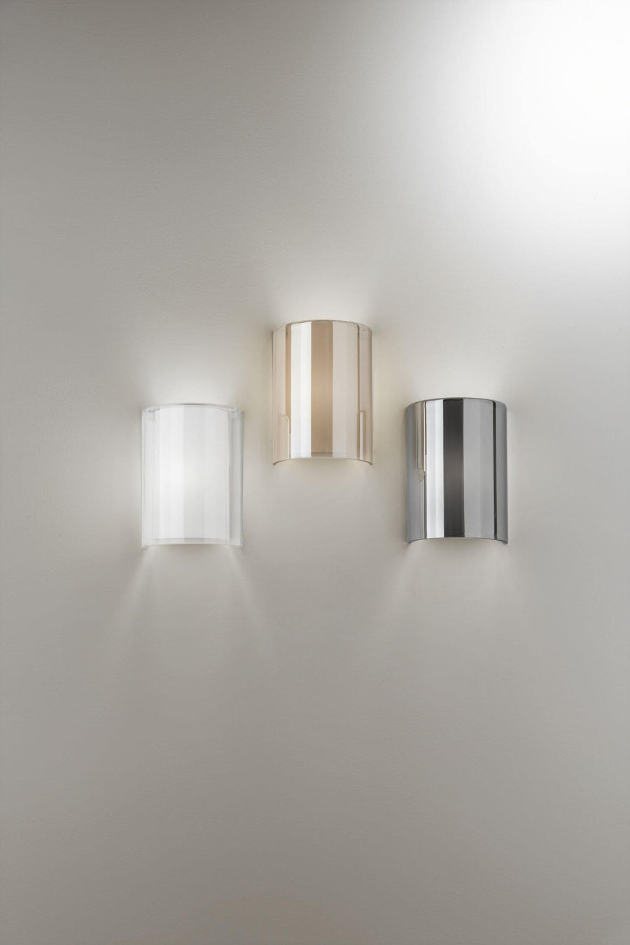 Trois appliques murales cintrées de face, coloris transparent, ambre rosé et chrome poli
