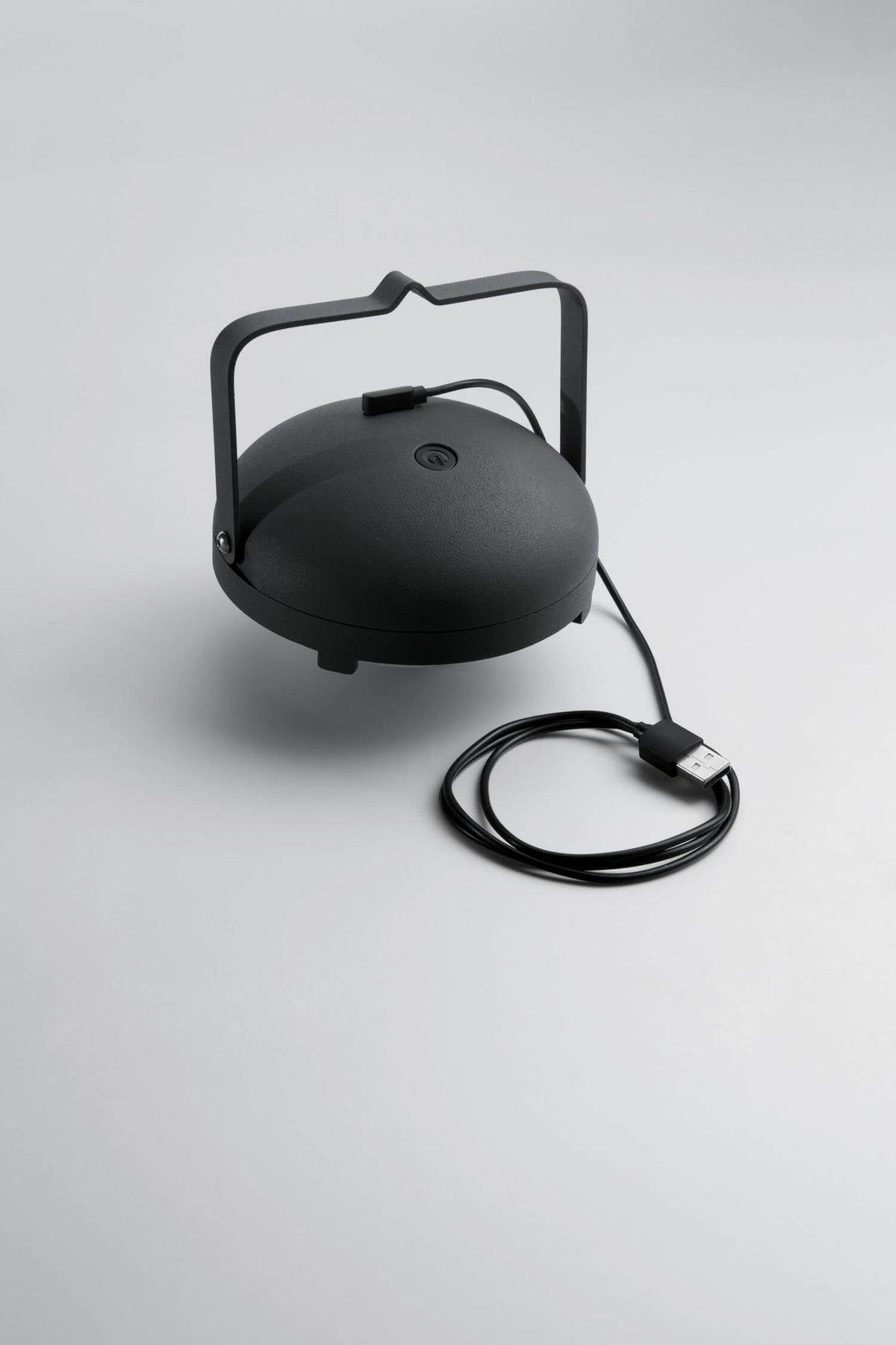 Détail du socle retourné avec bouton et câble de recharge USB