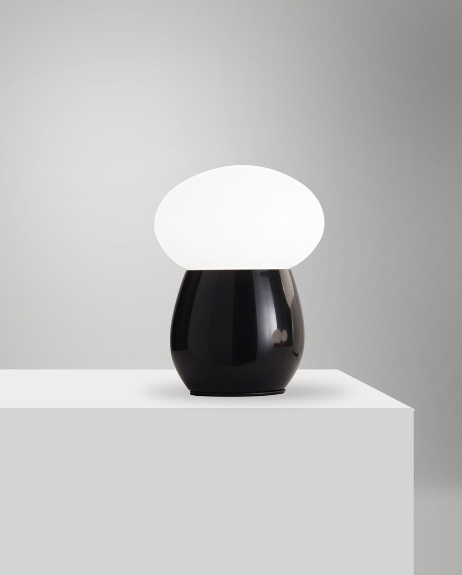 Lampe présentée sur un socle blanc, éclairage allumé, fond gris clair uni