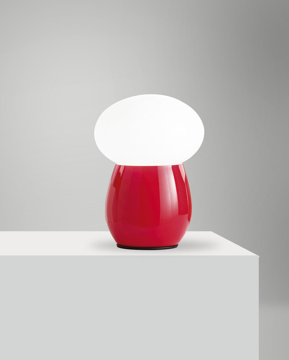 Lampe rouge présentée de loin sur un socle blanc, éclairage diffus