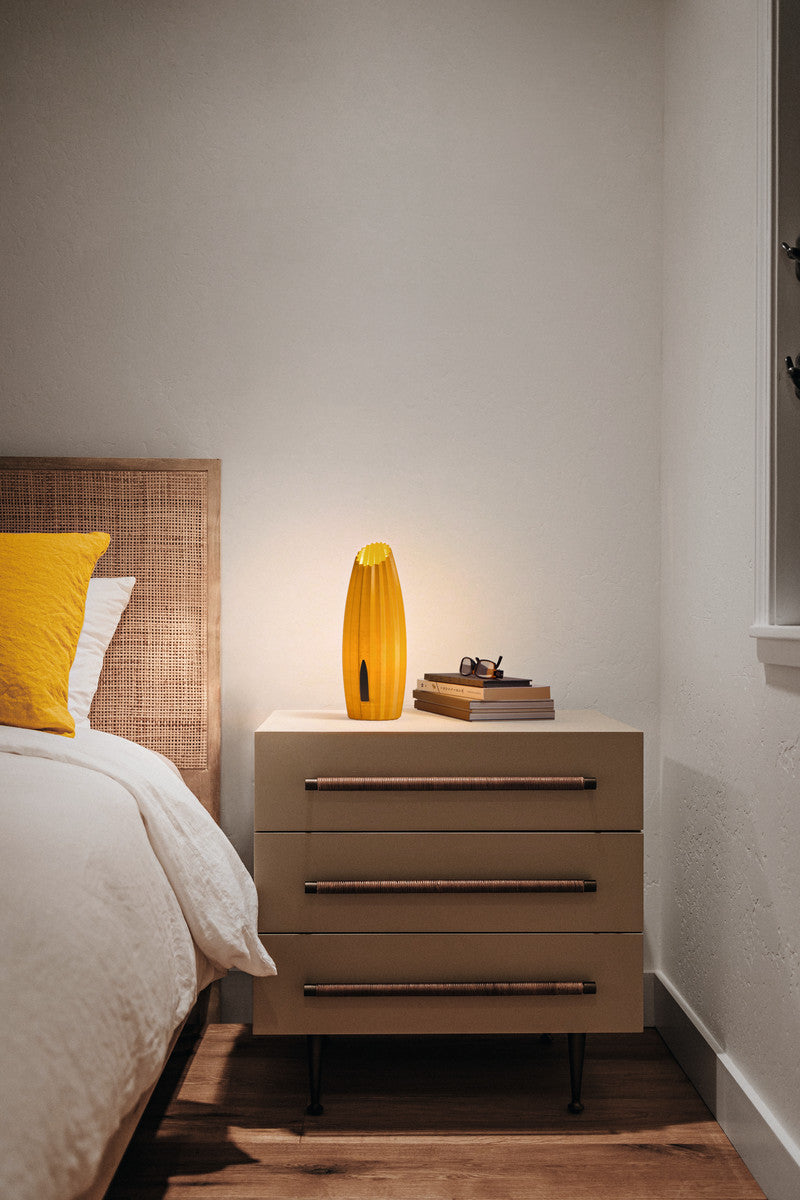 Mise en ambiance nocturne, lampe jaune allumée sur une table de chevet en chambre