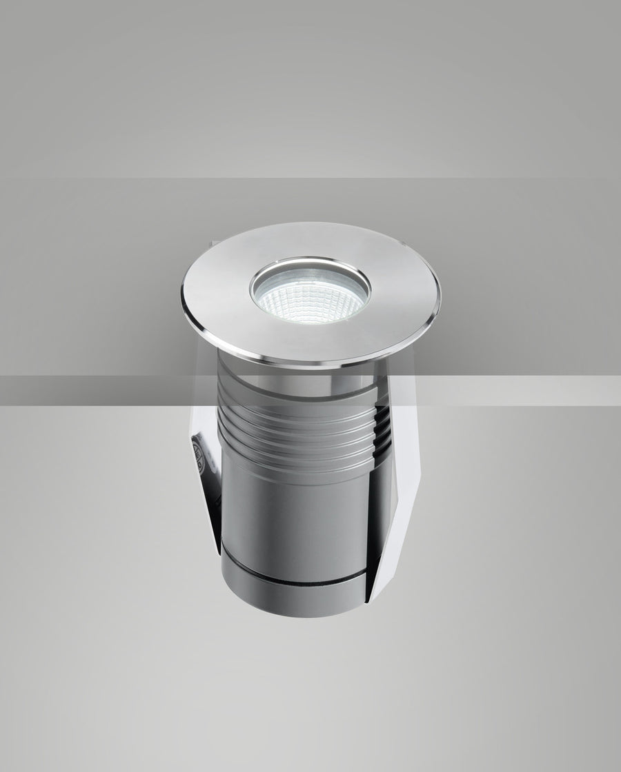 Vue plongeante du luminaire allumé, lentille LED et collerette ronde en acier poli