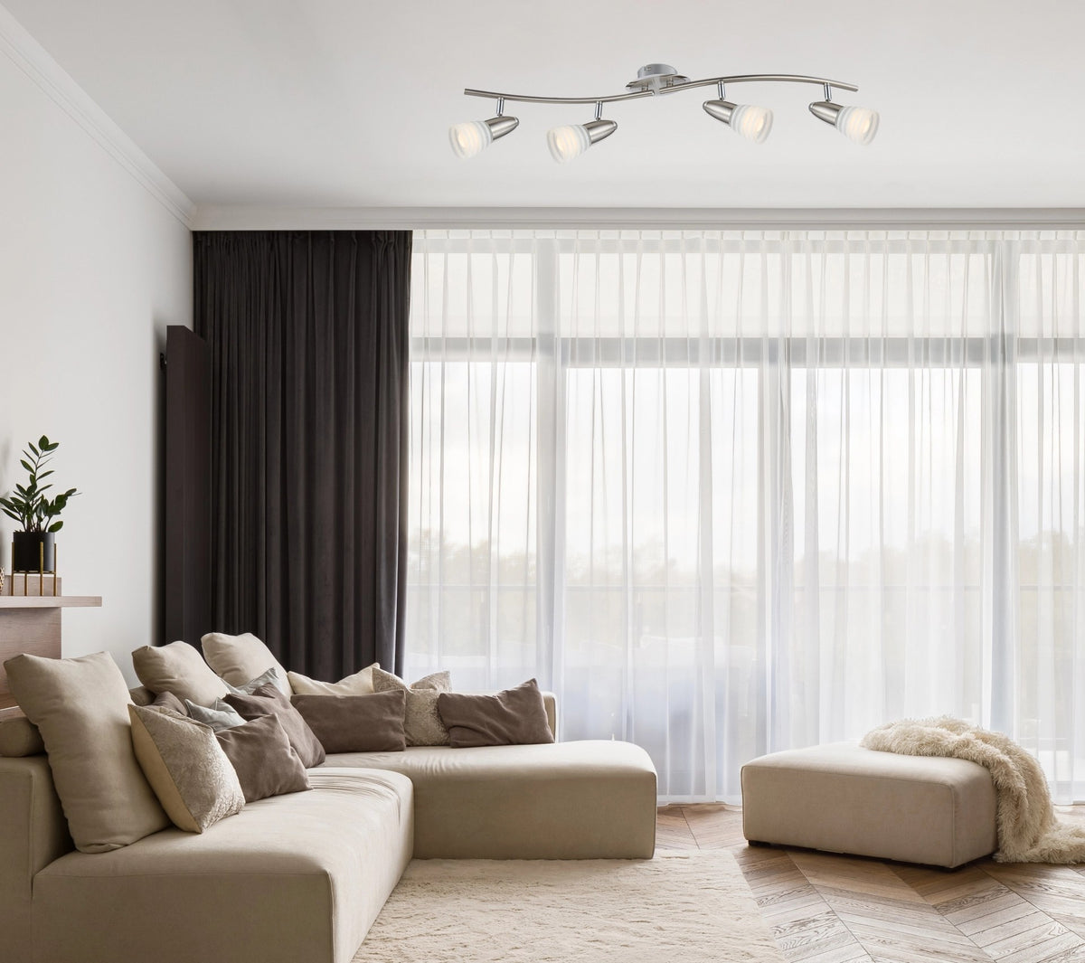 Mise en ambiance dans un salon clair, plafonnier allumé au-dessus d'un canapé beige