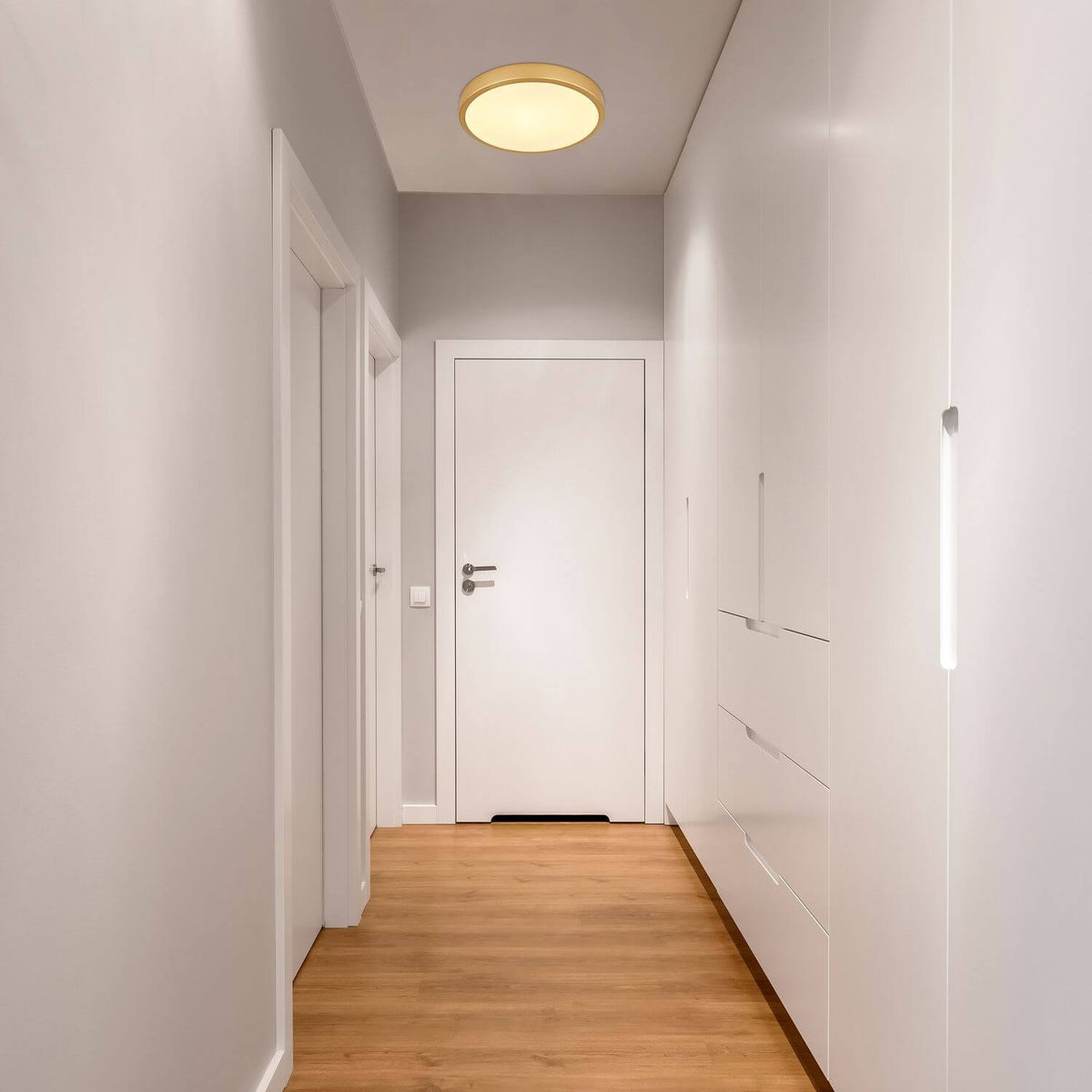 Mise en ambiance du plafonnier doré installé au plafond d'un couloir blanc moderne
