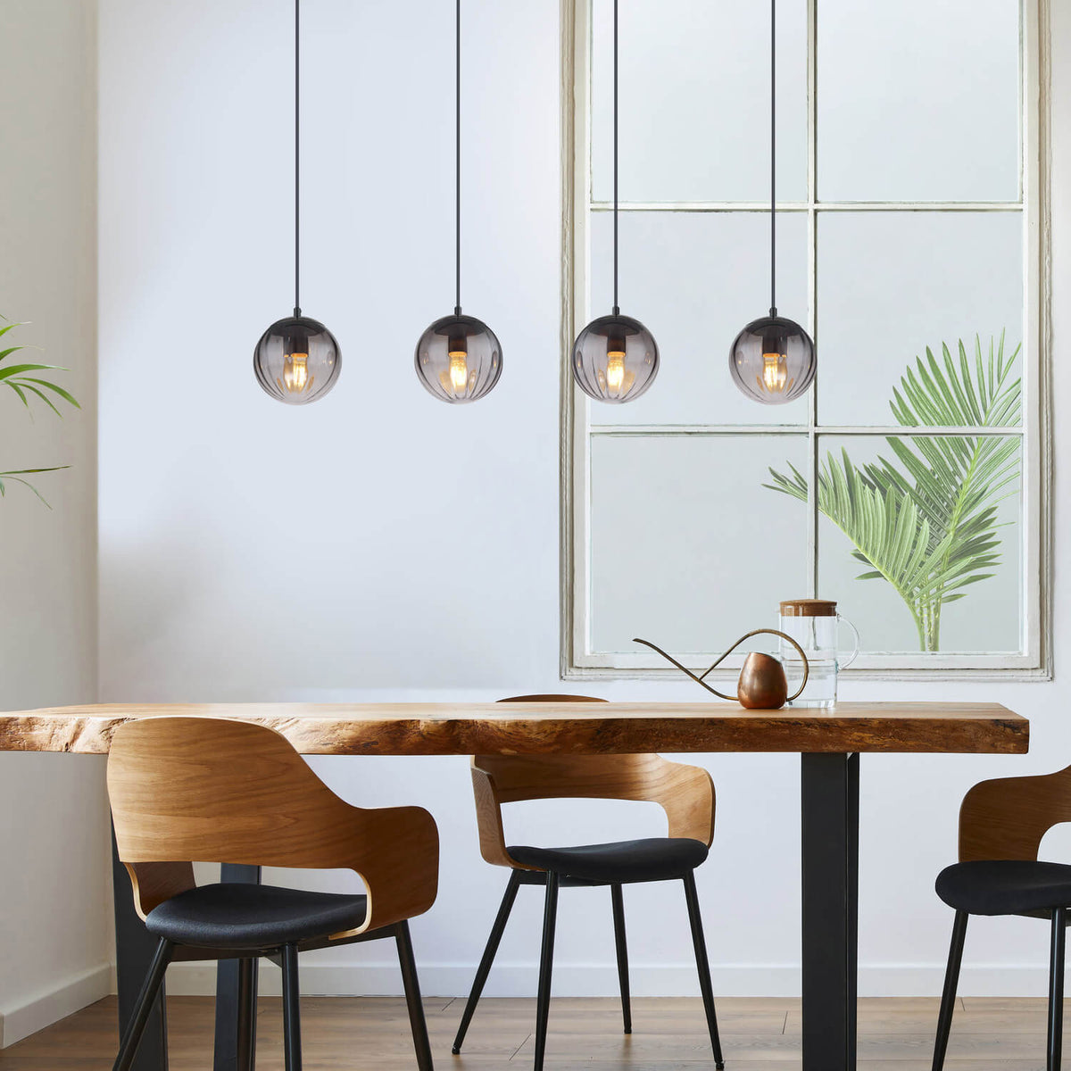 Mise en ambiance au-dessus d'une table en bois, suspension allumée dans une salle à manger