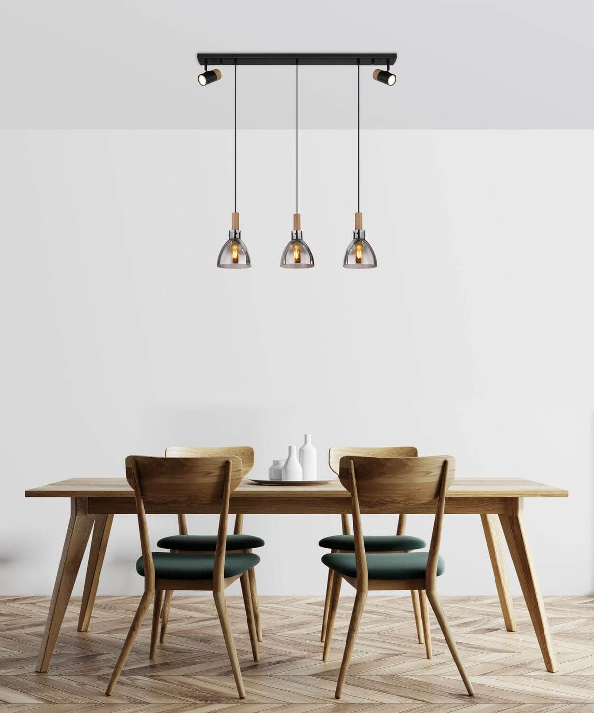 Mise en scène au-dessus d'une table en bois avec chaises vertes, suspension allumée.