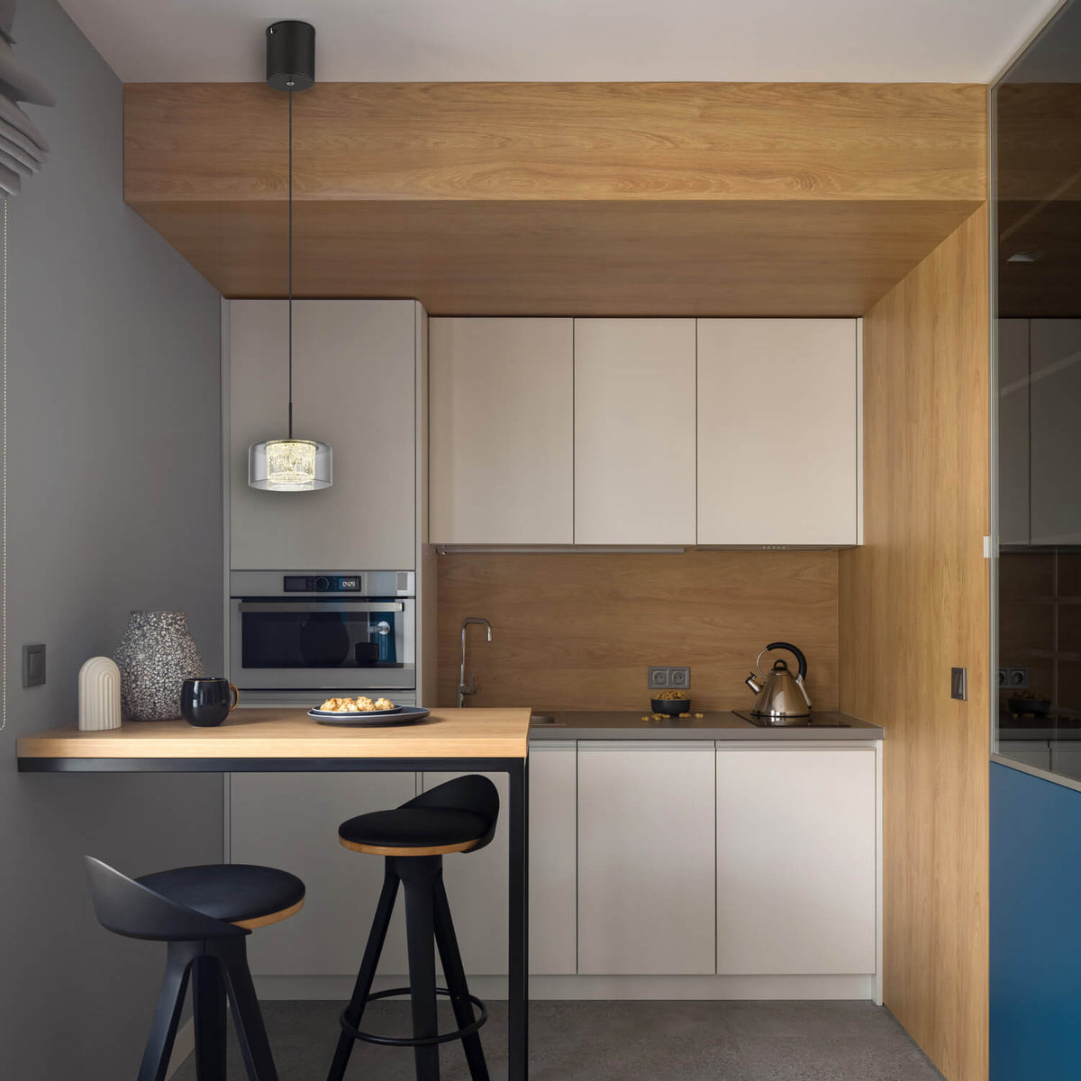 Mise en ambiance dans une cuisine moderne, suspension allumée au-dessus d'un îlot.