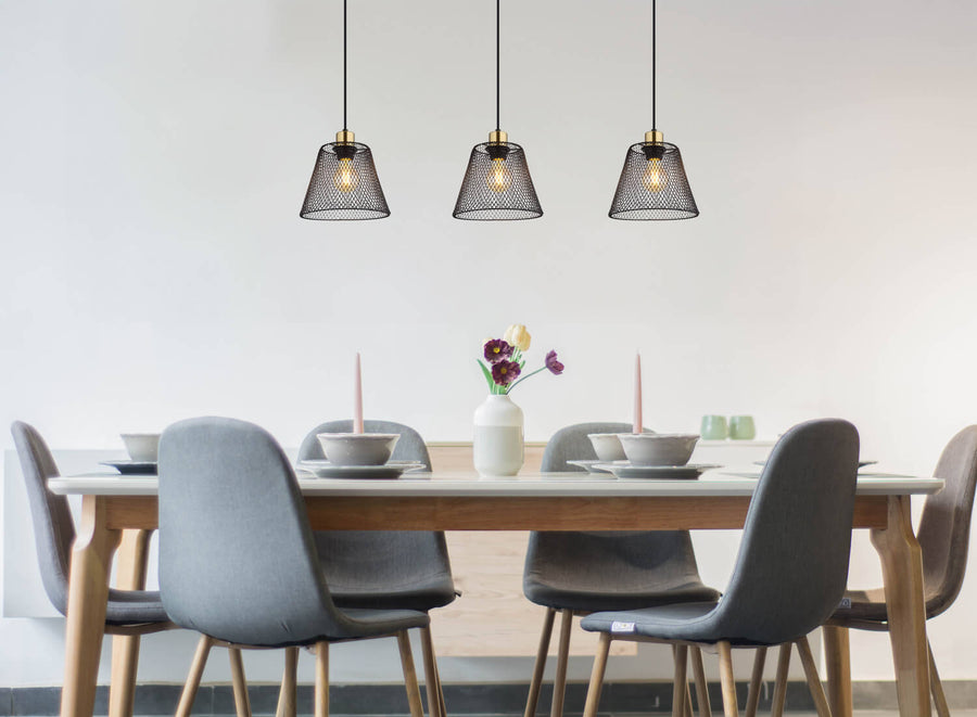 Suspension installée au-dessus d'une table à manger en bois, chaises grises et décoration.