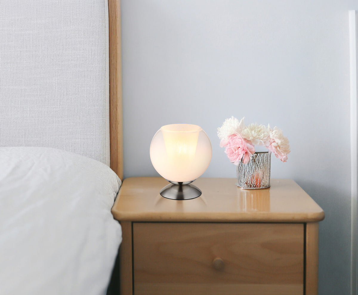 Lampe posée sur une table de chevet en bois près d'un lit