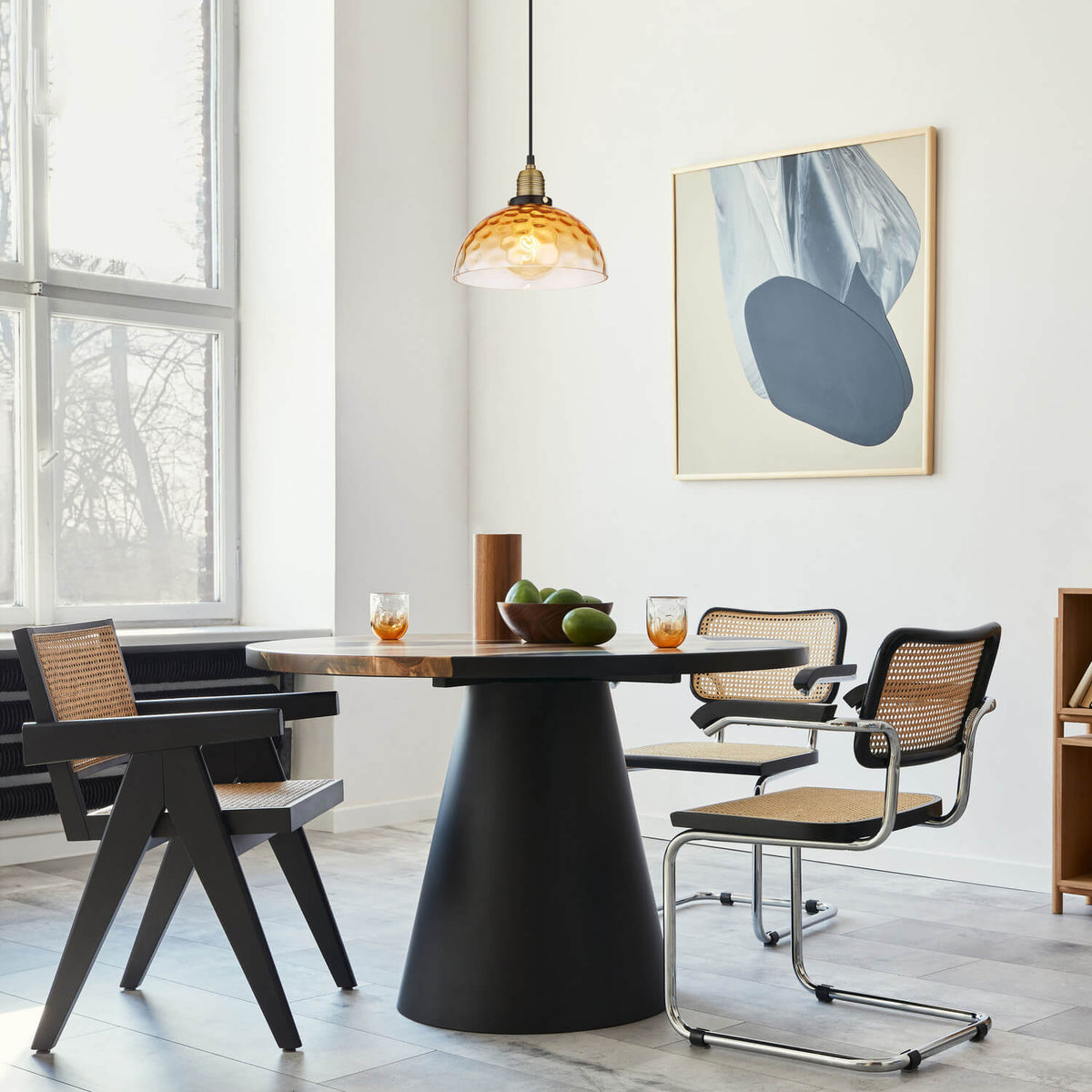 Suspension allumée au-dessus d'une table à manger, dans un intérieur contemporain.