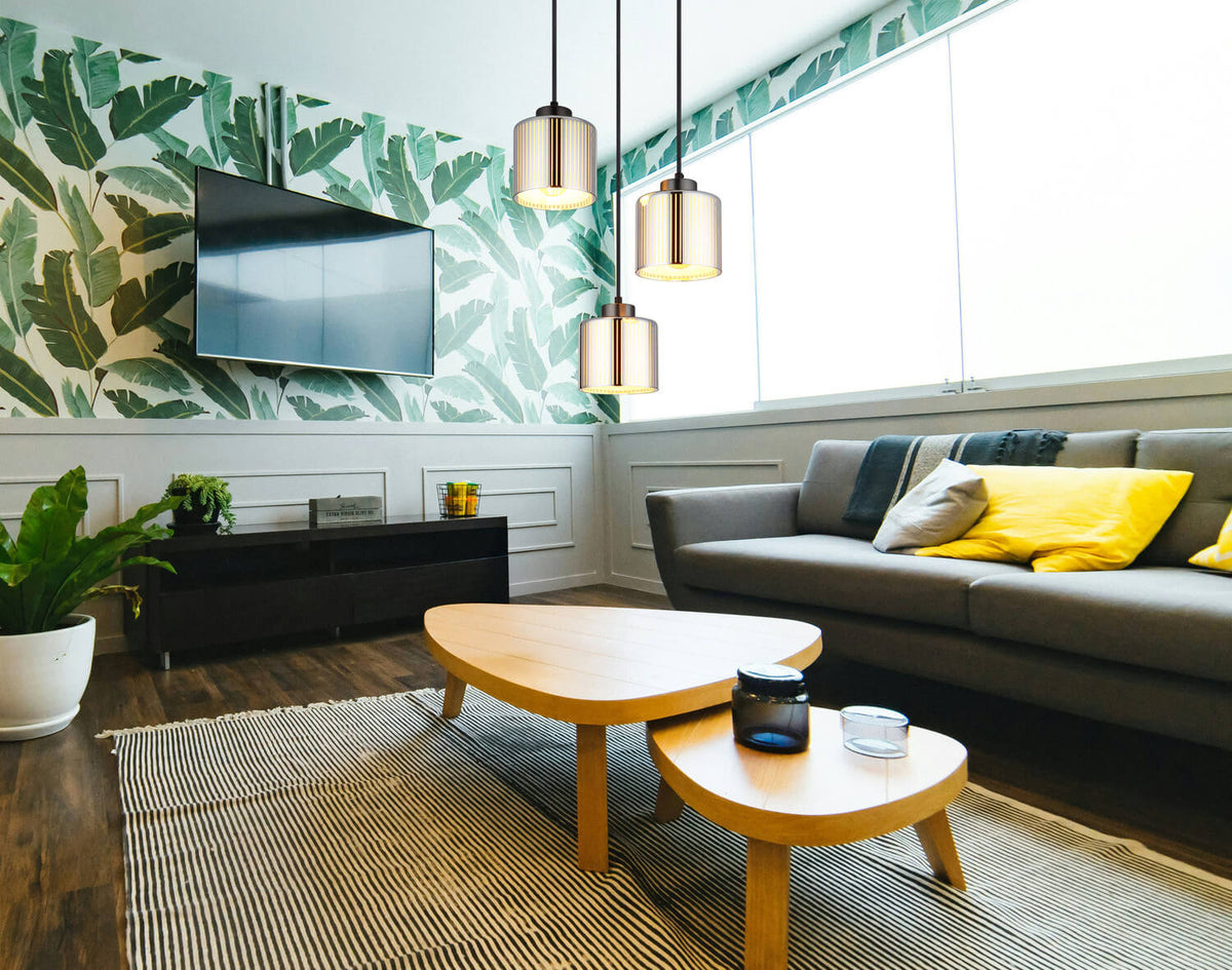 Mise en ambiance salon, suspension allumée au-dessus table basse bois et mur feuillage