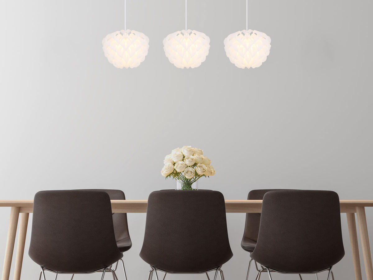 Mise en ambiance au-dessus d'une table en bois avec chaises noires et roses blanches