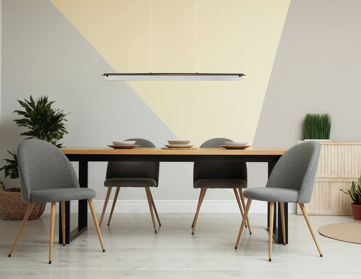 Suspension linéaire noire éclairant une table à manger en bois clair.