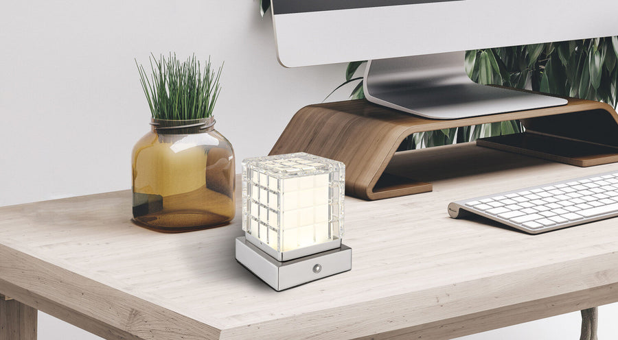Lampe posée sur un bureau en bois près d'un ordinateur et d'une plante verte