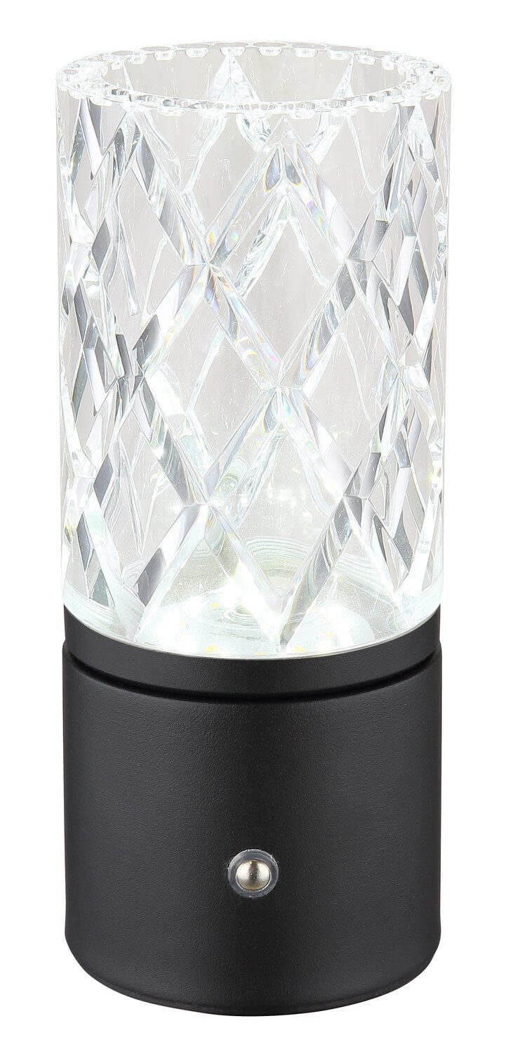 Vue de face de la lampe allumée, reflets cristallins sur l’abat-jour, base cylindrique noire et interrupteur.