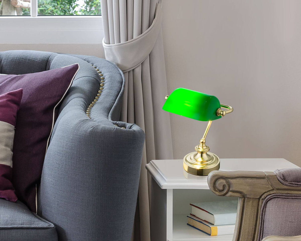 Lampe à poser posée sur une table de chevet blanche près d'un canapé gris.