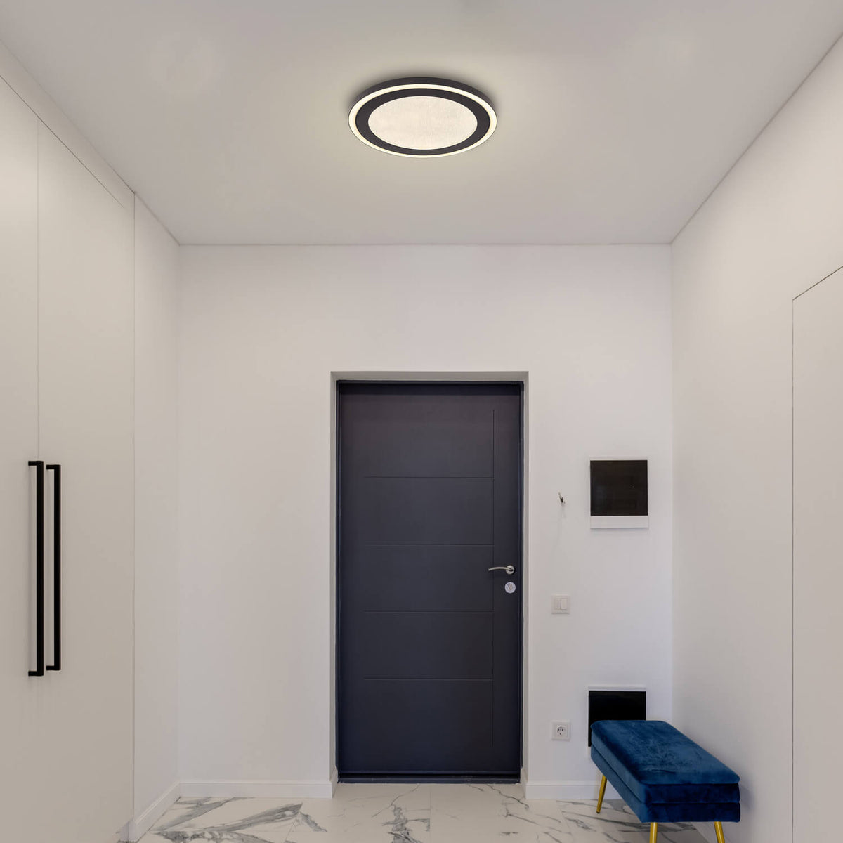 Mise en ambiance dans une entrée blanche, plafonnier vu au-dessus d'une porte