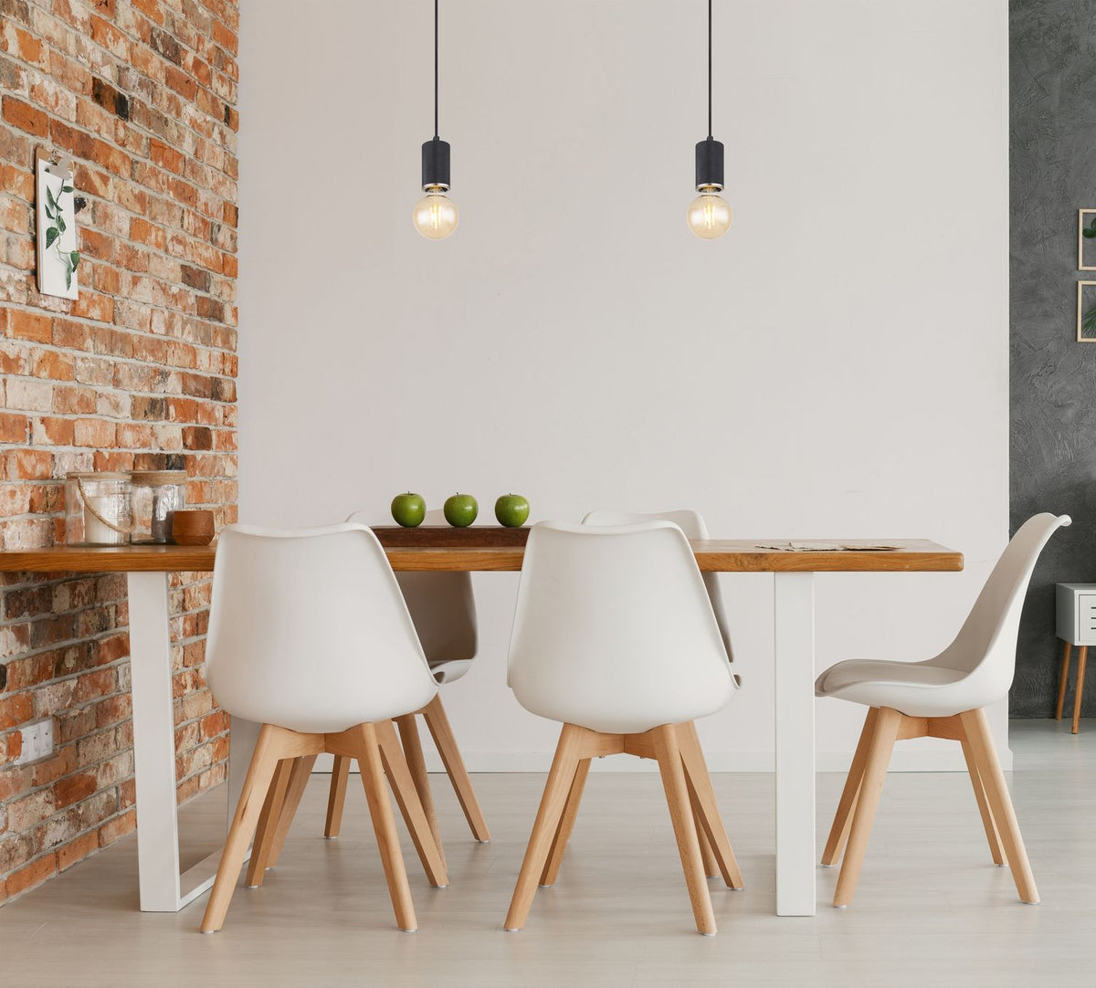 Mise en ambiance au-dessus d'une table en bois avec chaises blanches et mur brique.