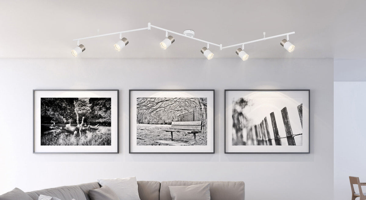 Mise en ambiance au plafond éclairant trois cadres photo au-dessus d'un canapé