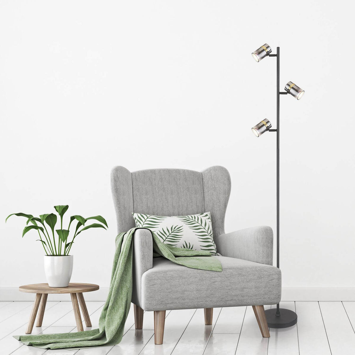 Mise en ambiance salon avec fauteuil gris, plaid vert et plante près du lampadaire.