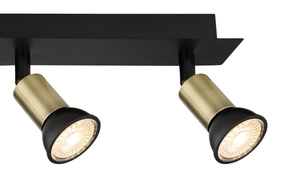 Détail de deux têtes en laiton brossé et noir avec ampoules allumées.