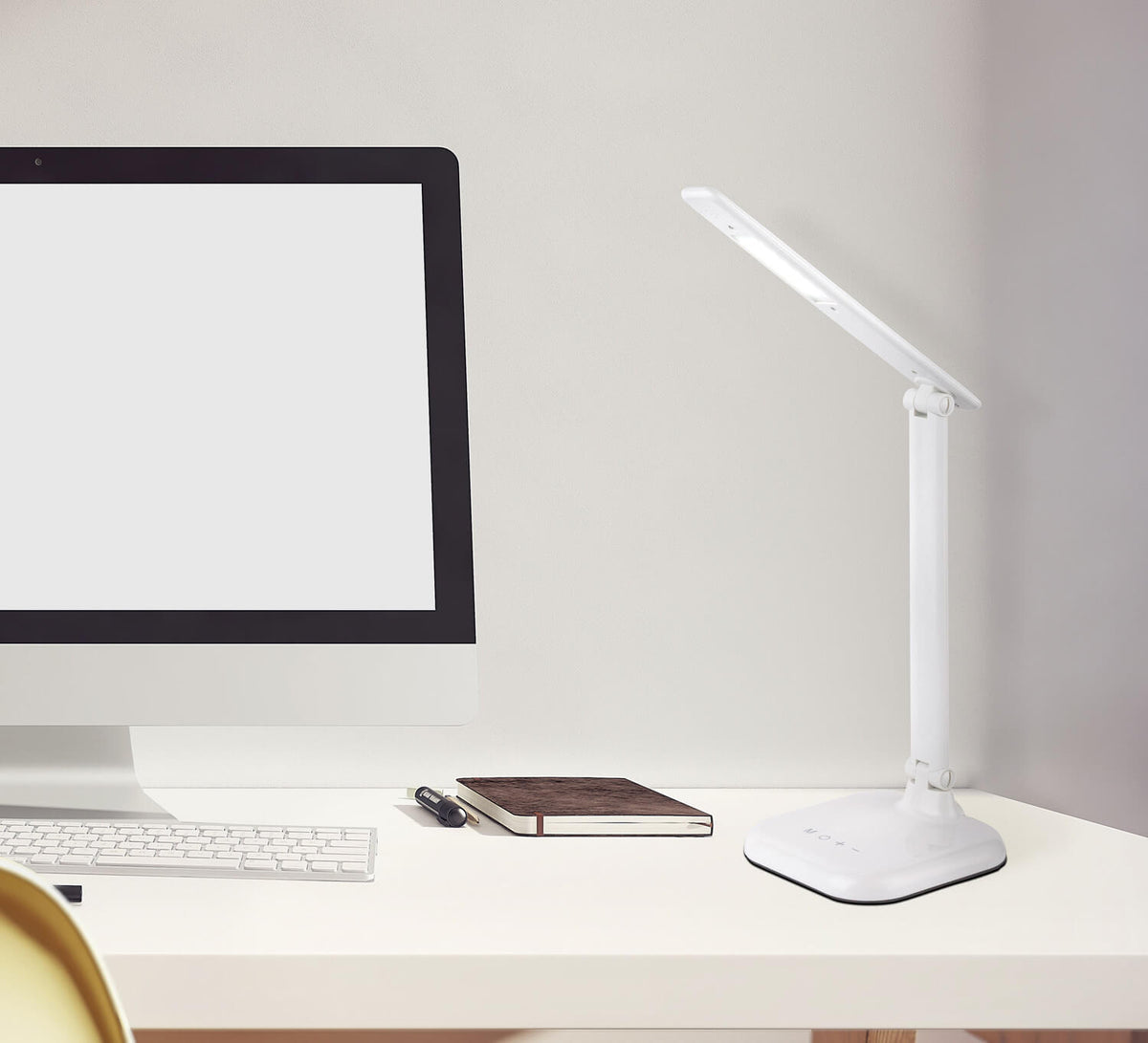 Mise en ambiance sur un bureau blanc près d'un écran et d'un carnet