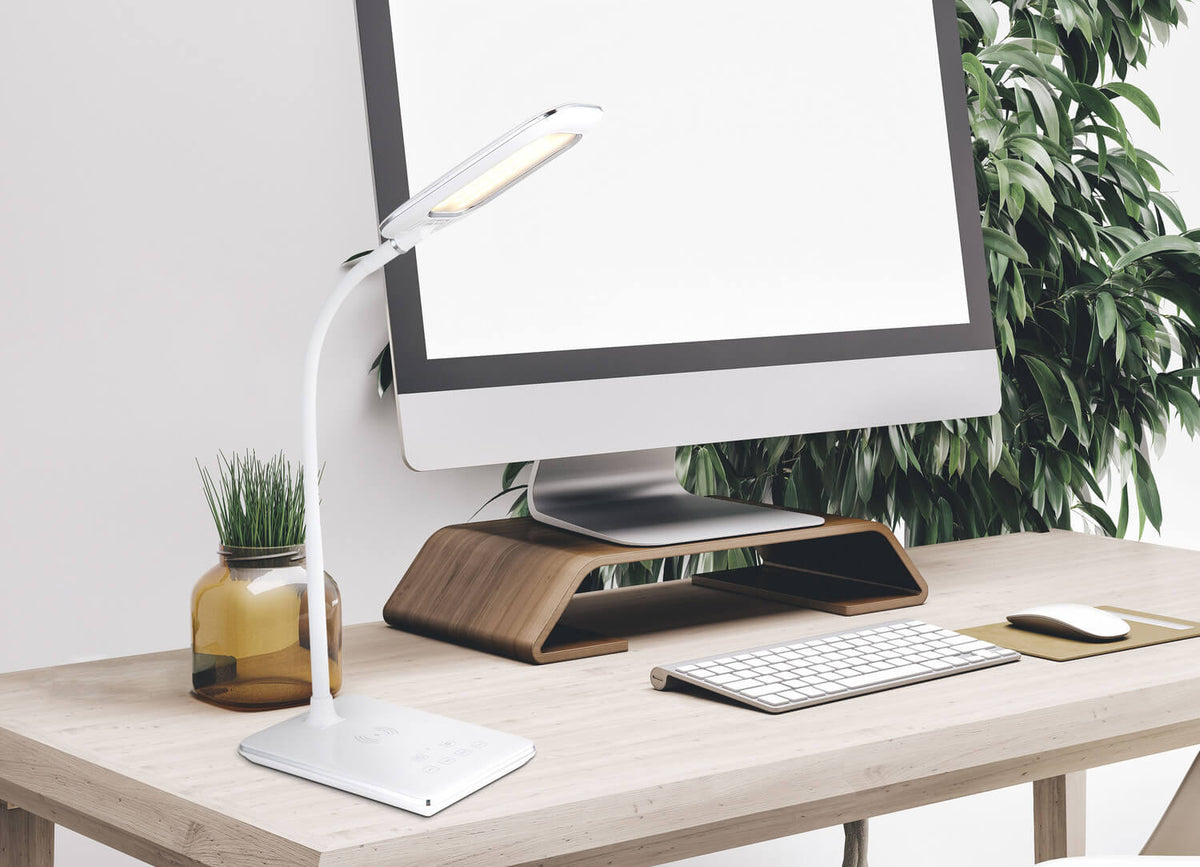 Lampe allumée posée sur un bureau en bois devant un écran d'ordinateur