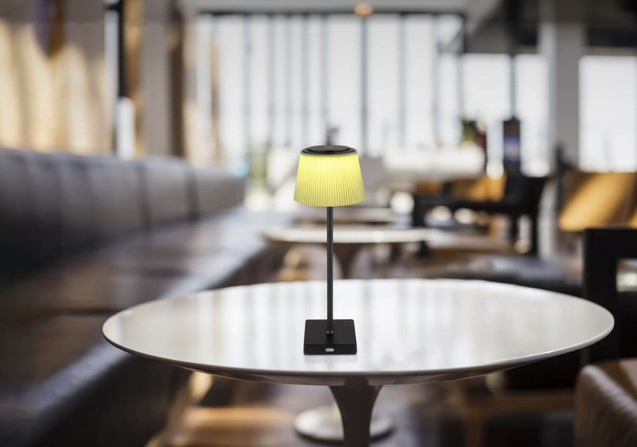 Lampe allumée posée sur une table ronde dans un intérieur contemporain flou.