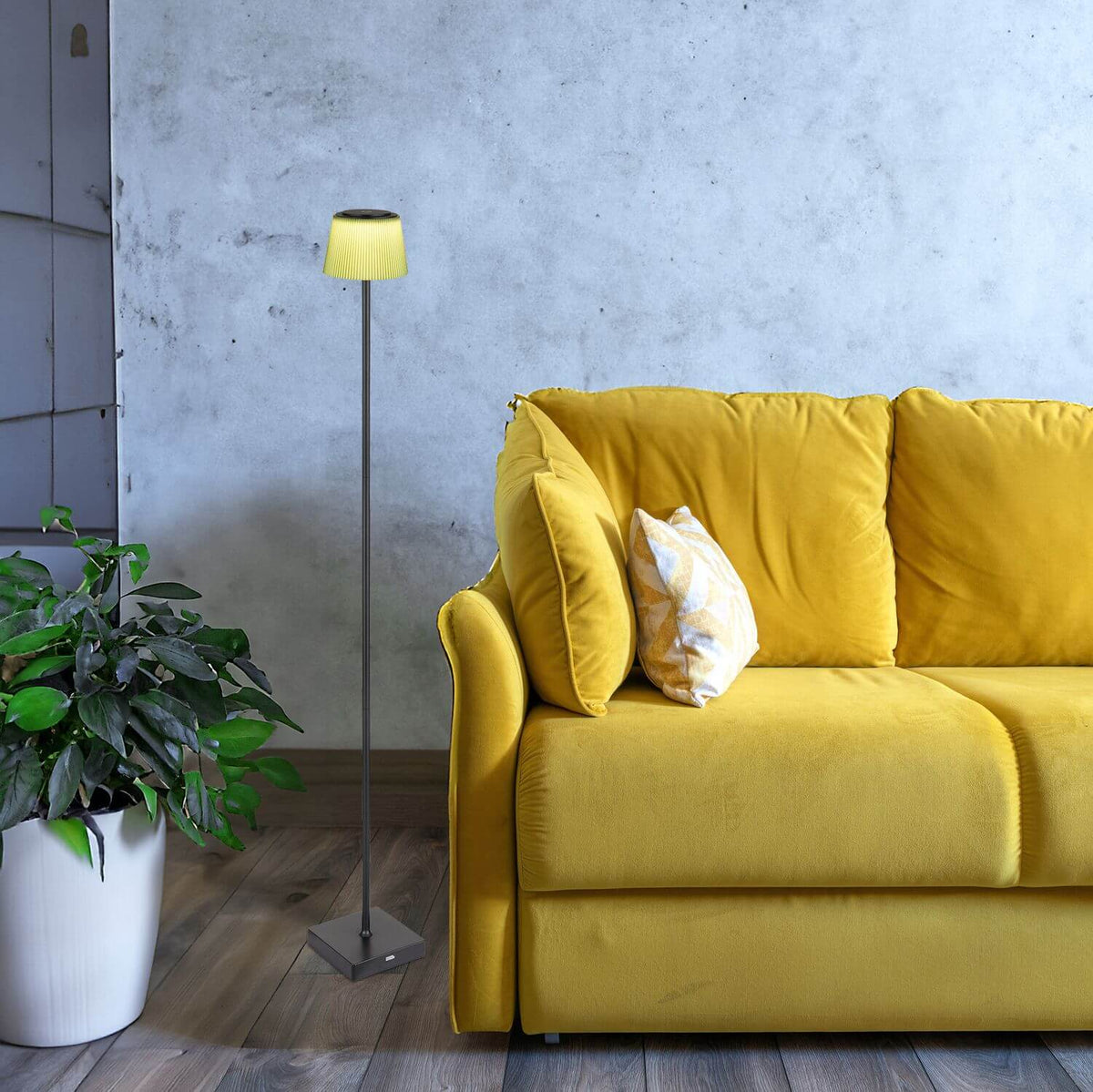 Mise en ambiance dans un salon avec canapé jaune, mur béton et plante verte