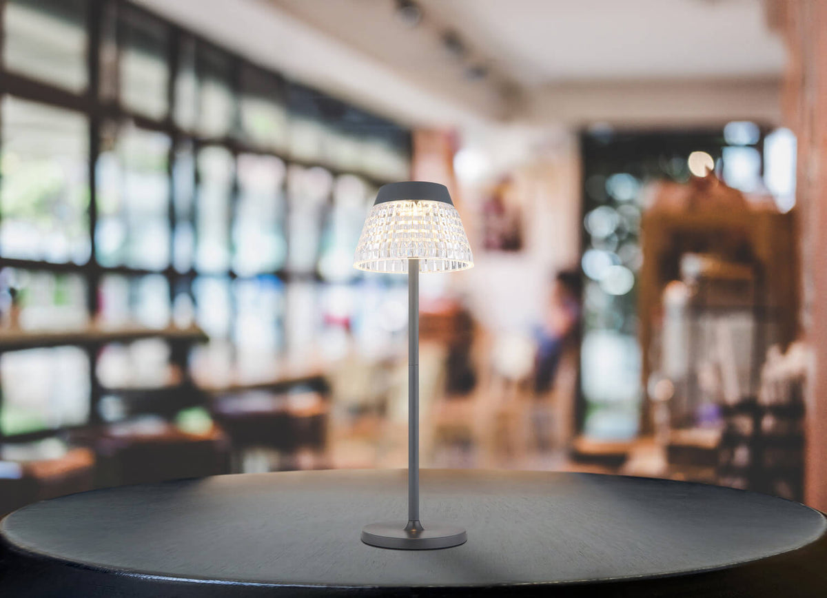 Lampe allumée posée sur une table dans un café, ambiance chaleureuse et floue.