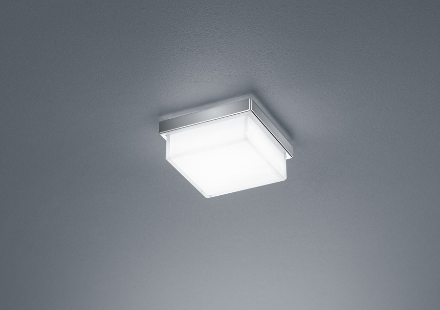 Gros plan sur la monture chromée et le diffuseur blanc carré du luminaire