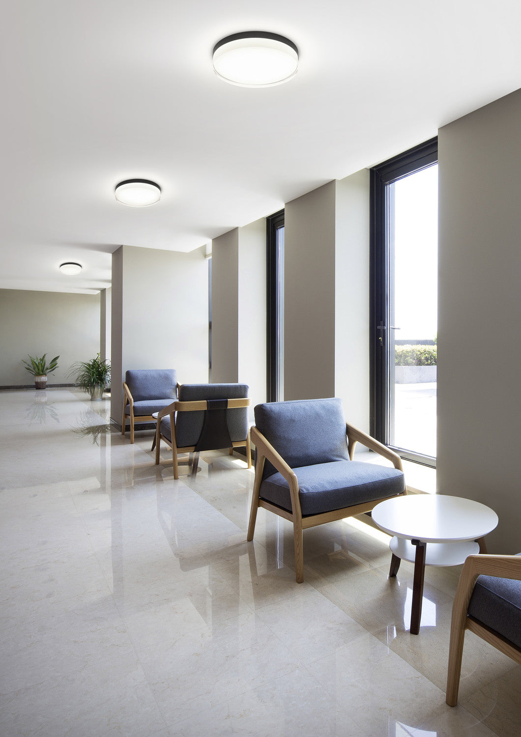 Plusieurs plafonniers ronds alignés au plafond d'un couloir contemporain lumineux