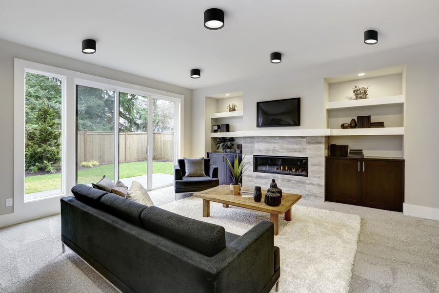 Salon contemporain avec plusieurs plafonniers noirs ronds fixés au plafond et décor moderne.