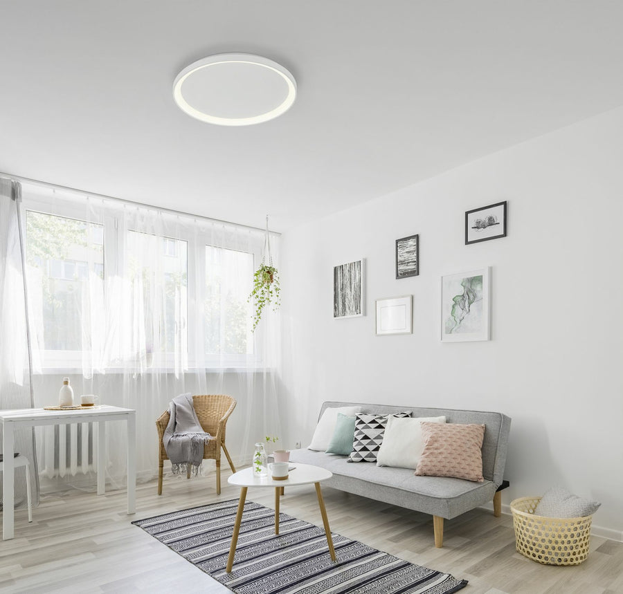 Plafonnier rond blanc allumé au plafond d'un salon scandinave lumineux et clair