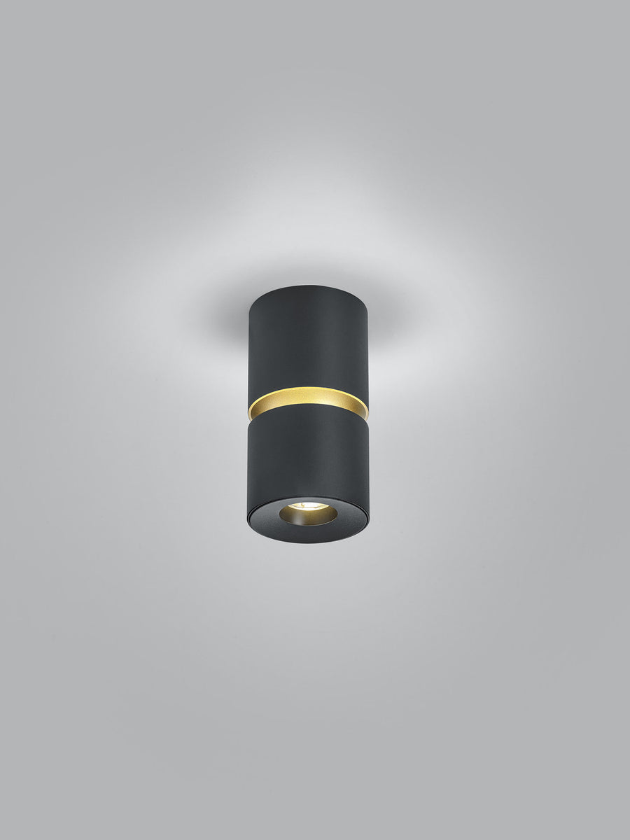 Vue de trois quarts du luminaire noir dévoilant la bague dorée centrale
