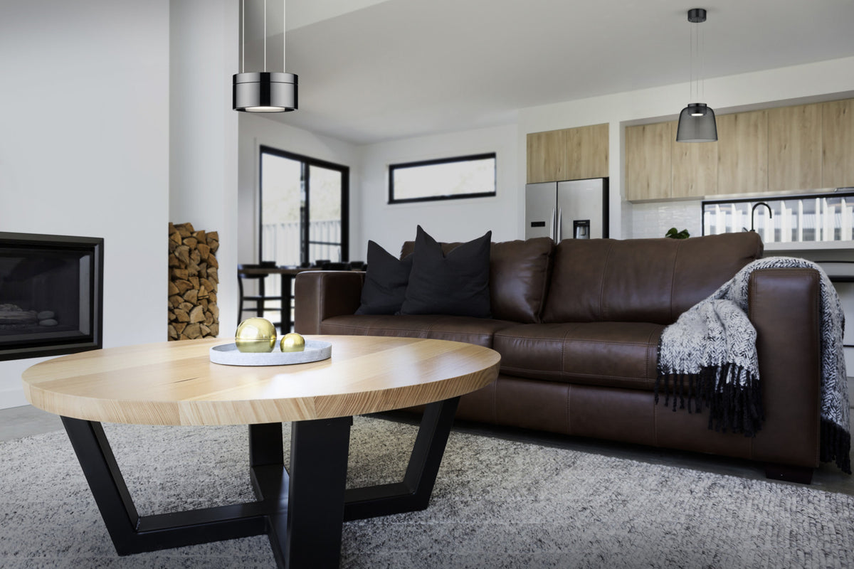 Mise en ambiance : suspension allumée au-dessus d'un salon avec canapé en cuir.