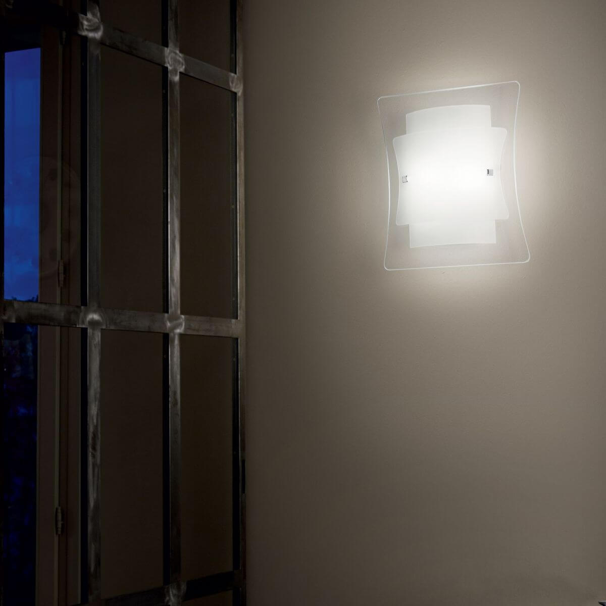 Mise en ambiance de l'applique allumée sur un mur beige près d'une fenêtre