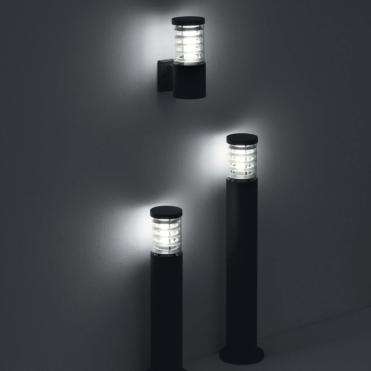 Trois luminaires extérieurs allumés dans une ambiance nocturne