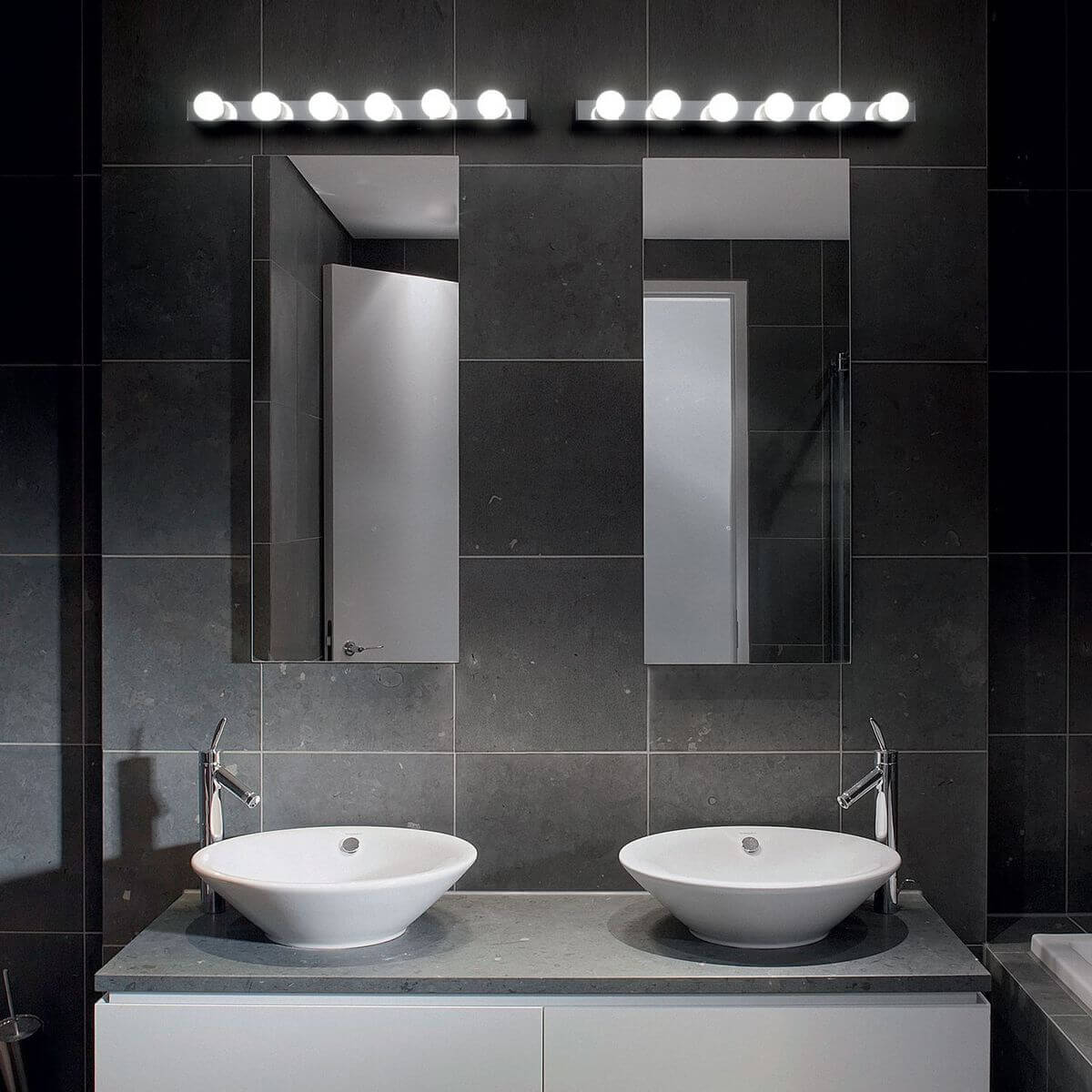 Mise en ambiance dans une salle de bain sombre, appliques allumées au-dessus de deux miroirs