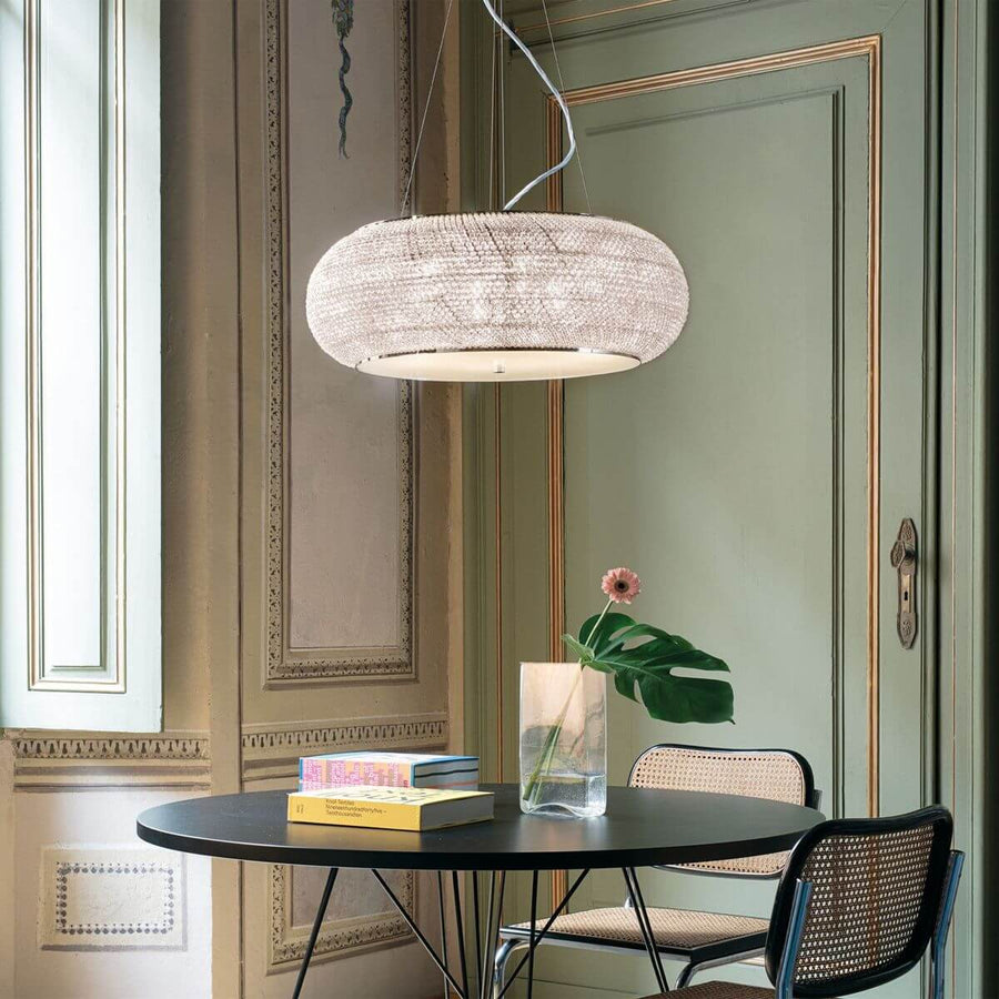 Suspension en cristal installée au-dessus d'une table ronde dans un salon vert