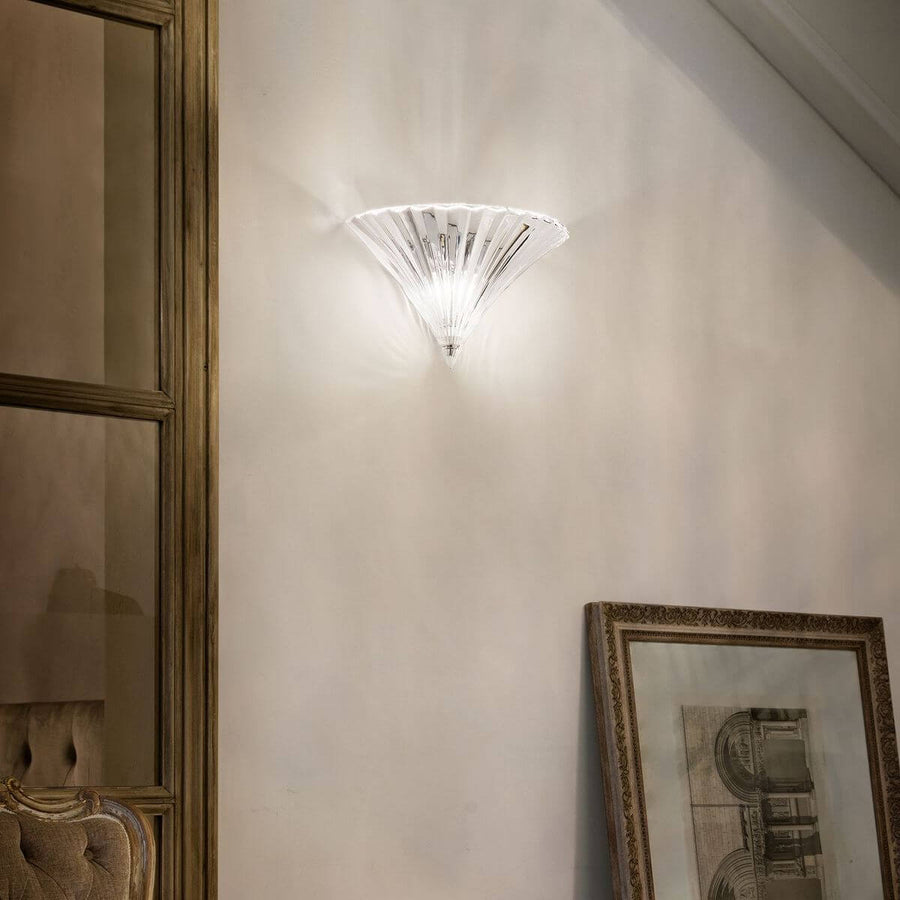 Applique allumée sur un mur beige, diffusant une lumière chaude près d'un miroir