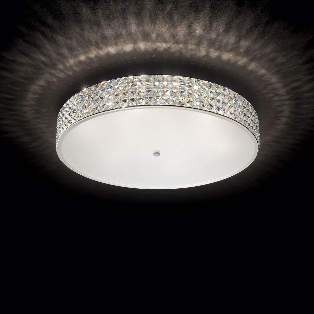 Luminaire allumé dans le noir, halo lumineux projeté au plafond par les cristaux