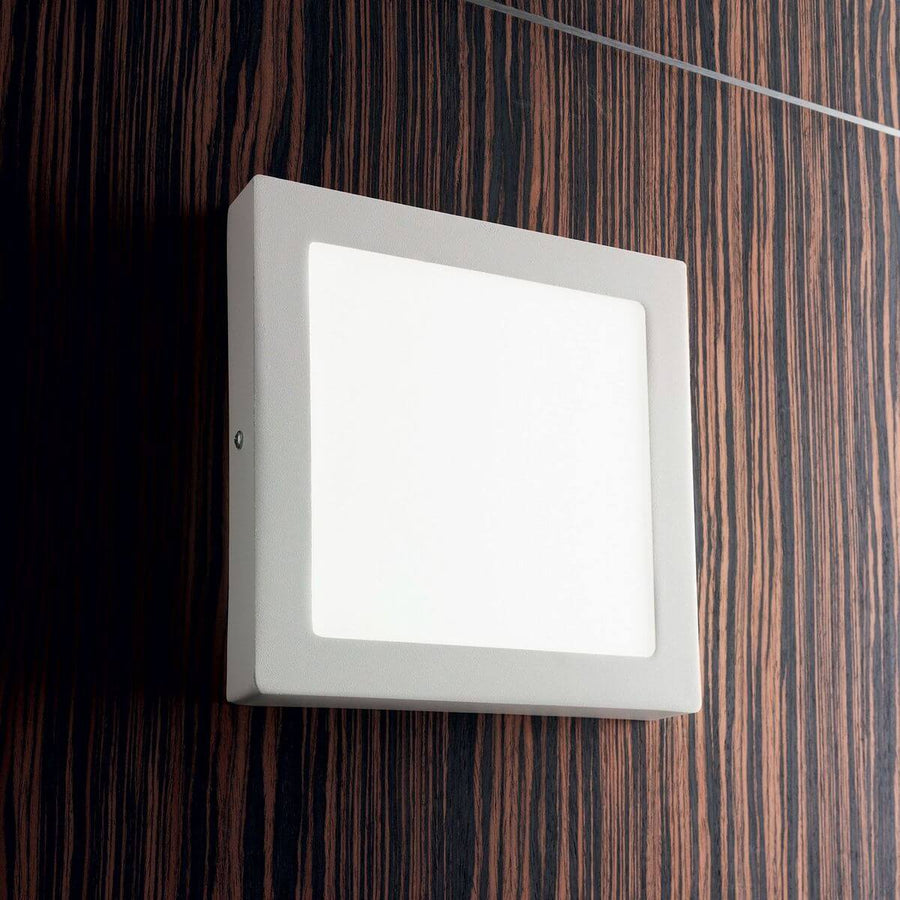 Vue de côté du luminaire blanc carré fixé sur une surface en bois strié