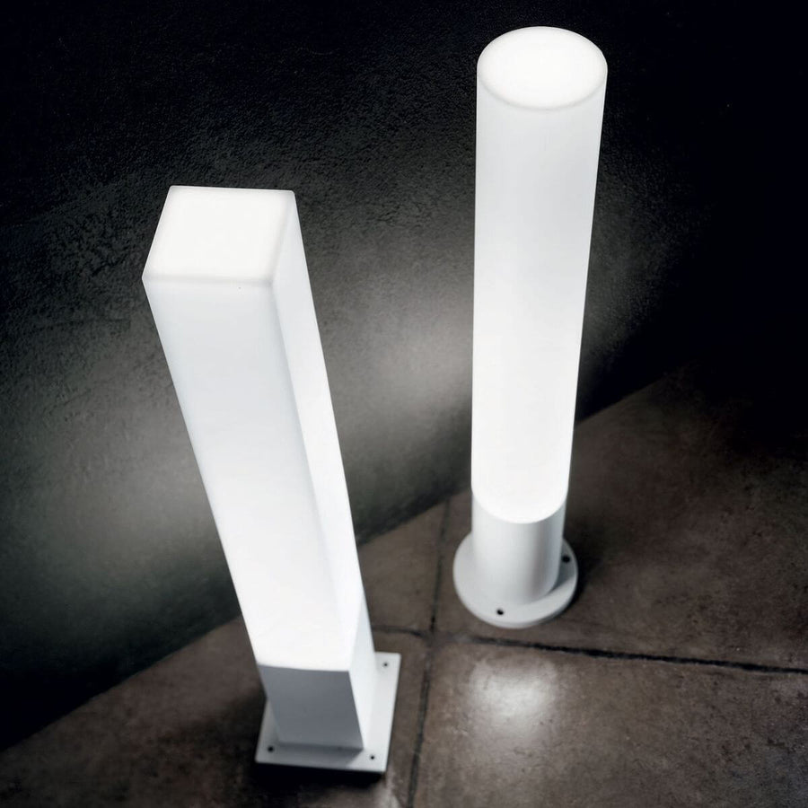 Deux bornes lumineuses allumées, carrée et cylindrique, installées de nuit sur une terrasse
